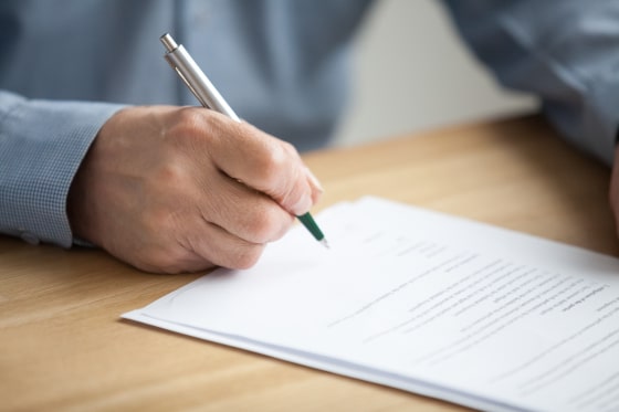Image of a person with a pen as they sign a Will