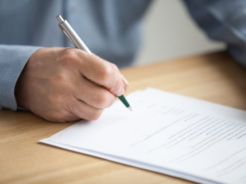 Image of a person with a pen as they sign a Will